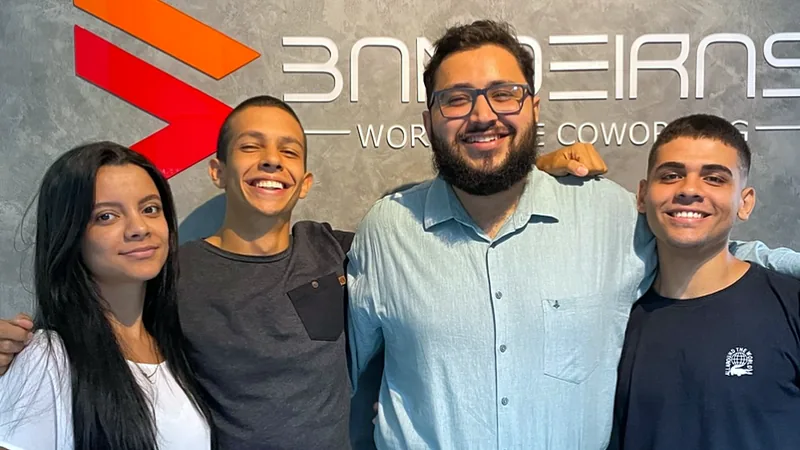 Equipe do Bandeiras Coworking na recepção, em frente ao logo
